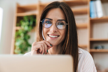 Wall Mural - Image of happy adult businesswoman smiling while working with laptop