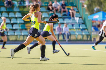 Wall Mural - Young women playing field hockey game on the pitch