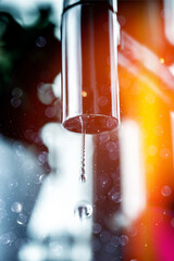 water dripping from modern polished kitchen tap with bokeh dust around the air