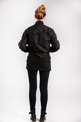 Canvas Print - Young female wearing a black jacket standing against a white wall