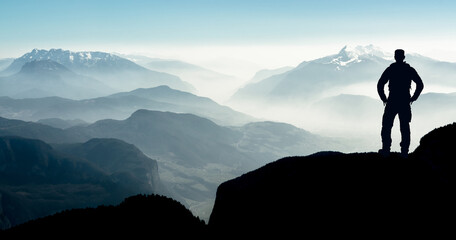 Poster - Spectacular layered mountain ranges with valley fog. Man Silhouette reaching summit enjoying freedom.