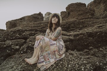 Canvas Print - Selective focus shot of a young caucasian female with tattoos wearing a dress and straw hat