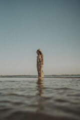 Poster - Young female with tattoos wearing a dress and straw hat on blurred ocean background