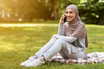 Wall Mural - Girl in hijab having pleasant conversation on smartphone