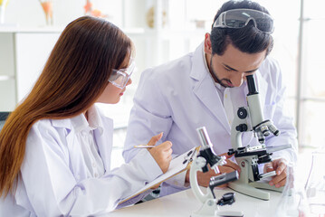 Wall Mural - attractive happiness scientist lab technician assistant analyzing sample in test tube and using micr