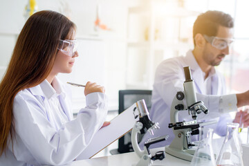 Wall Mural - attractive happiness scientist lab technician assistant analyzing sample in test tube and using micr