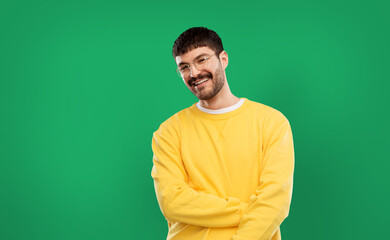 Wall Mural - people concept - smiling young man in glasses and yellow sweatshirt over emerald green background