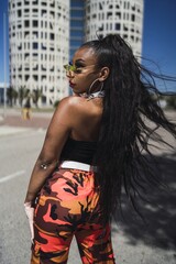 Poster - Vertical shot of an attractive African American female posing near a tall modern building