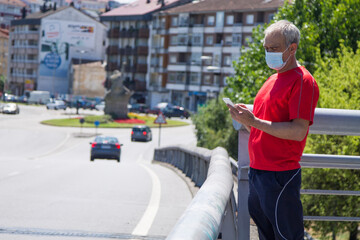 Wall Mural - man with mobile phone and medical mask on the street, concept of new normal