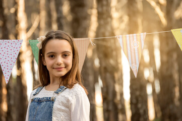 Portrait of a beautiful young girl, with flag decoration in a pine forest in the background