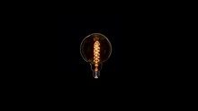 Edison Dirty Lamp With Dust Inside Glass, Flicker On Black Background. Amber Tungsten Color Old Vintage Retro Lamp Turn On And Off With Out Wire.