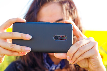 woman in the afternoon shoots on the phone in the field, close-up of the phone