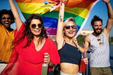 Happy group of people hanging out in the city waving LGBT with pride flag