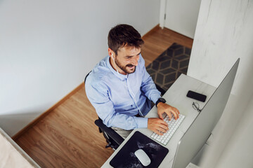 Top view of innovative handsome bearded businessman sitting in his home office and working on important project.