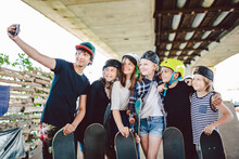 Group Of Friends Skateboarders Taking Selfie On Phone In Skate Park. Large Group Children With Skateboards Take Memory Photo On Ramp In Skatepark. Group Kids Make Joint Photo On Smartphone
