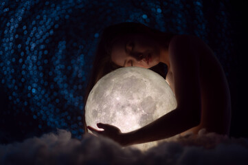 Wall Mural - beautiful girl holds the moon against the background of stars and clouds, fairy tale picture, magic,