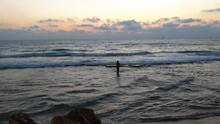 A Fisherman Walks In The Sea, On The Beach Of Tel Aviv.
The Beach At Sunset, Waves Breaking On The Beach
Ship Sails Deep Into The Sea, Orange-colored Sunset,
Tel Aviv Beach