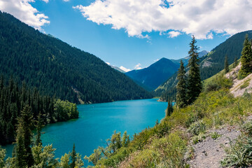 Beautiful view to Kolsai or Saty lake with mountains background. Summer vacation concept. Scenic travel background. Travel in Kazakhstan concept.