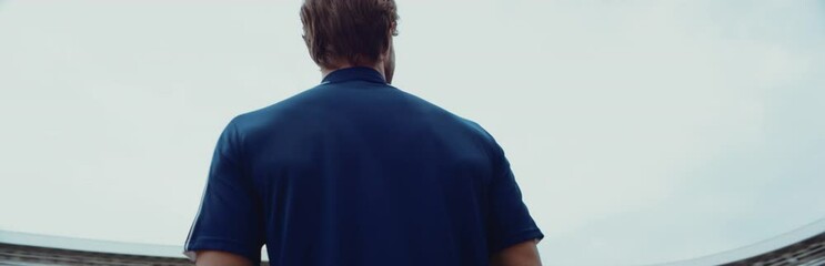 Wall Mural - Young adult Caucasian male sportsman soccer player entering and admiring a large empty stadium. Shot on RED Cinema camera