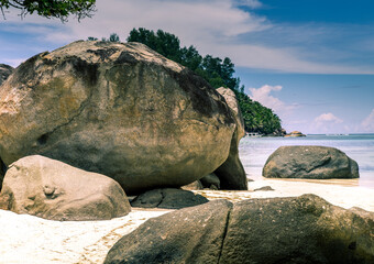 Tropical and heavenly beach with blue sky, coconut trees, white sands, crystal clear waters, surrounded by huge granite boulders rocks at seychelles islands