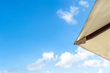 Wall Mural - White sun umbrella on blue sky with clouds