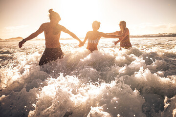 Wall Mural - Playful summer people enjoy the ocean wave together in friendship playing and having fun together - concept of tourism and travel lifestyle - three friends have fun with waves and sea