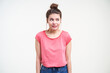© timtimphoto - Studio photo of young puzzled brown haired female looking confusedly aside and keeping hands down while standing over white background in pink t-shirt