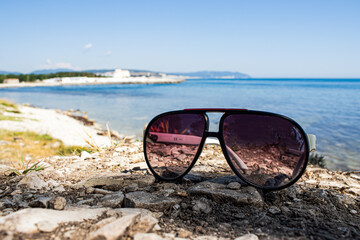 sunglasses are lying on the beach, in bright Sunny summer weather, against the sea of the resort city of Gelendzhik