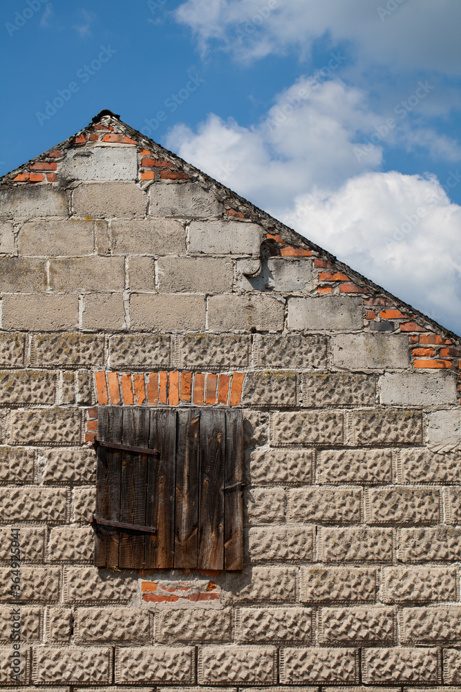 Szczytowa ściana starego wiejskiego gospodarczego budynku z drewnianymi drzwiczkami prowadzącymi na strych. - obrazy, fototapety, plakaty 