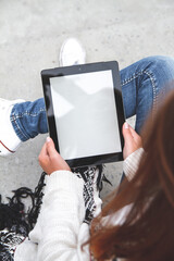 Young woman holding and using tablet with blank screen in hand top view.