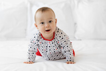Cute Baby Girl Crawling On White Bed Looking At Camera