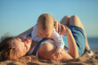 © Sk Elena - Happy family, mother and baby lies on the sunset sea beach. Parent with children on summer vacations.