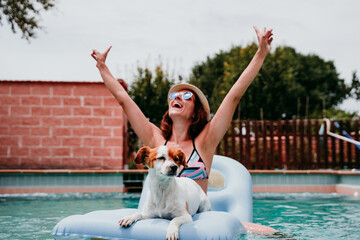 Wall Mural - happy woman and dog in a pool having fun. dog sitting on inflatable and playing with owner. Summer time