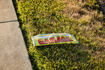 an abandon garage sake sign laying along side of the road