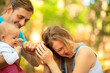 © Sk Elena - Happy family spent time together outdoors. Portrait of mother, father and baby. The child grabbed mom by the hair. Summer time.
