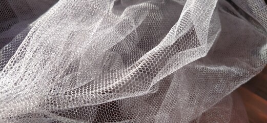 white thin mesh fabric. Fabric for veils, curtains, mosquito nets, tulle and other products of light industry. Synthetic Crumpled tulle.