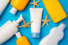 Sunscreen Cream Bottles With Sea Shells On Blue Background