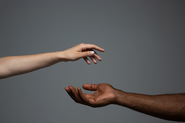 touch of god. racial tolerance. respect social unity. african and caucasian hands gesturing on gray 