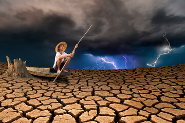 Man sitting on boat float on dry river with extreme weather background metaphor climate change and nature disaster