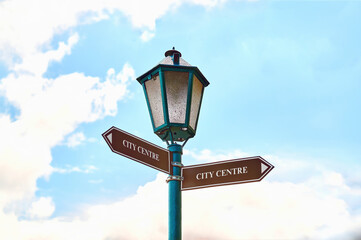 Street lamp with two pointers on a background of blue sky with clouds.