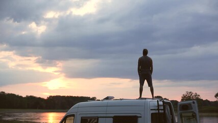 Wall Mural - man standing on the roof of his camper van at sunset