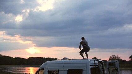 Wall Mural - Man on top of the roof of his camper van at sunset