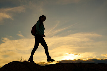 Wall Mural - young woman traveler hiking with backpack on the beautiful rocky trail at summer sunset. travel and 