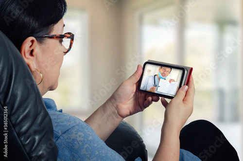 This mobile app lets a GP doctor treat his female patient remotely via video-chat. Mature woman attentively looks and listens to the doc on the screen of her mobile phone.
