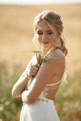 Wall Mural - Beautiful girl in a white dress. Woman in a summer field