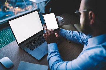 Fototapete - Businessman using wireless connection for synchronizing tablet and netbook with mock up screens share files during remote job, male entrepreneur updating software on portable pc sitting at desktop