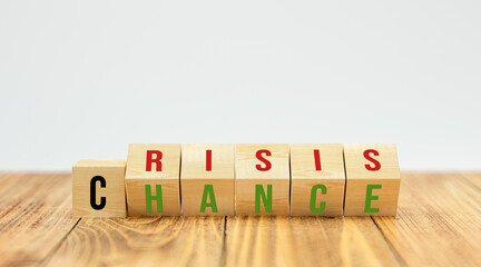 flipping cubes showing both words CRISIS and CHANCE at the same time on wooden table and white background