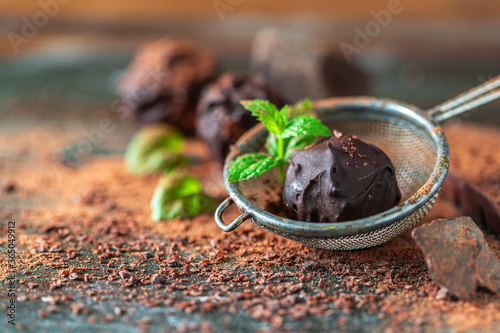 Fotografía Delicious chocolate truffles with mint, cocoa powder and dark chocolate on a dark wooden background