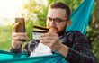 © mykolastock - Cheerful male entering bank card details on smartphone while ordering goods online