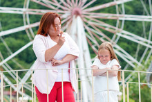 Family Portrait. The Mother Shakes Her Finger At Her Daughter For Her Capricious Behavior. Ferris Wheel In The Background. Concept Of Family Holidays And Summer Vacations